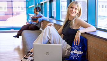 young blonde white woman relaxing in hallway with SUNY Ulster bag