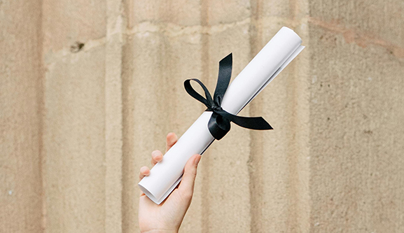 diploma tied with ribbon in hand