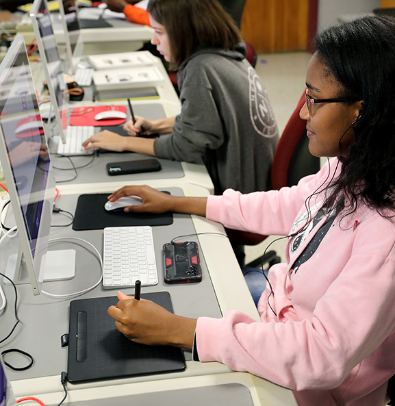 student using mouse on computer in classroom