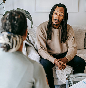 black man talks to other person from couch