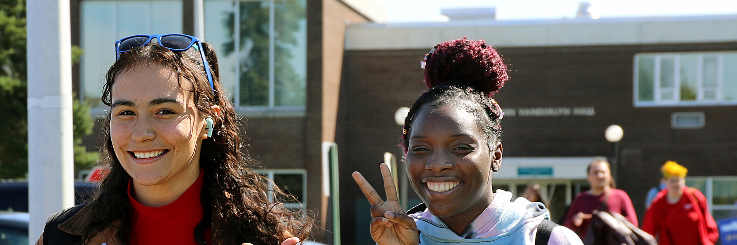 Students walking outside, one is throwing a peace sign