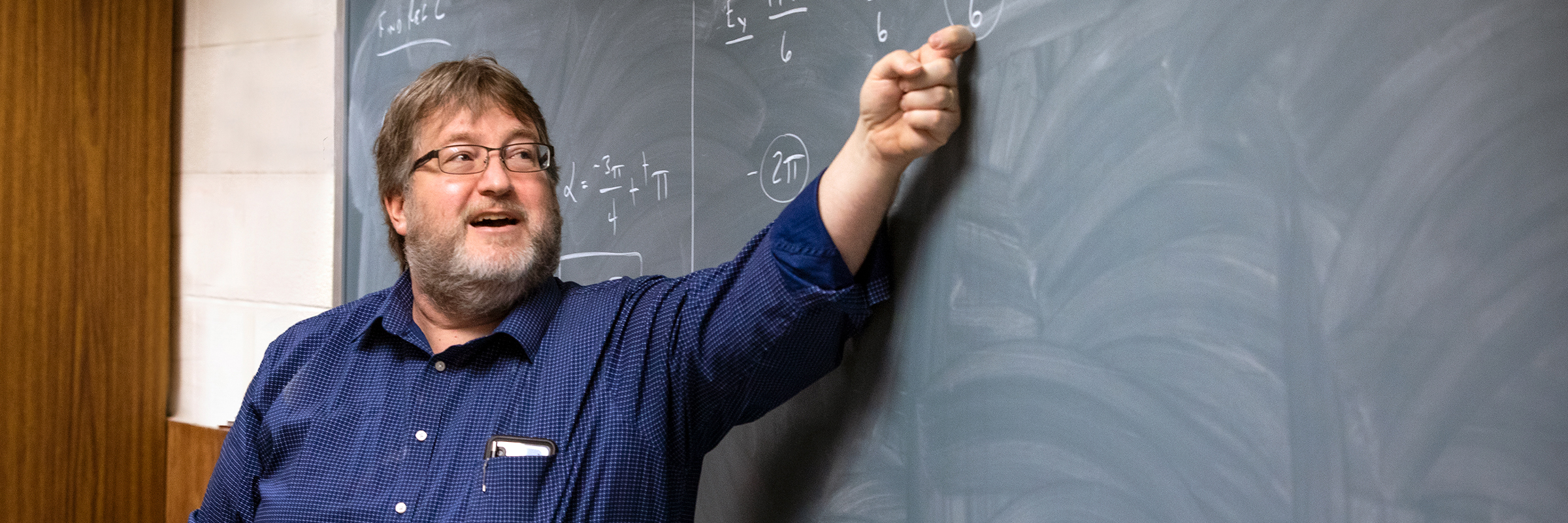 math teacher in front of chalkboard with math problems