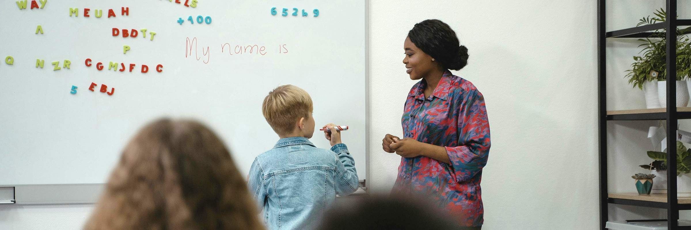 teacher in classroom with child and whiteboard