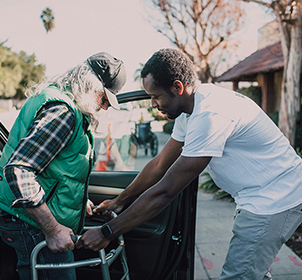 man helping older man with walker