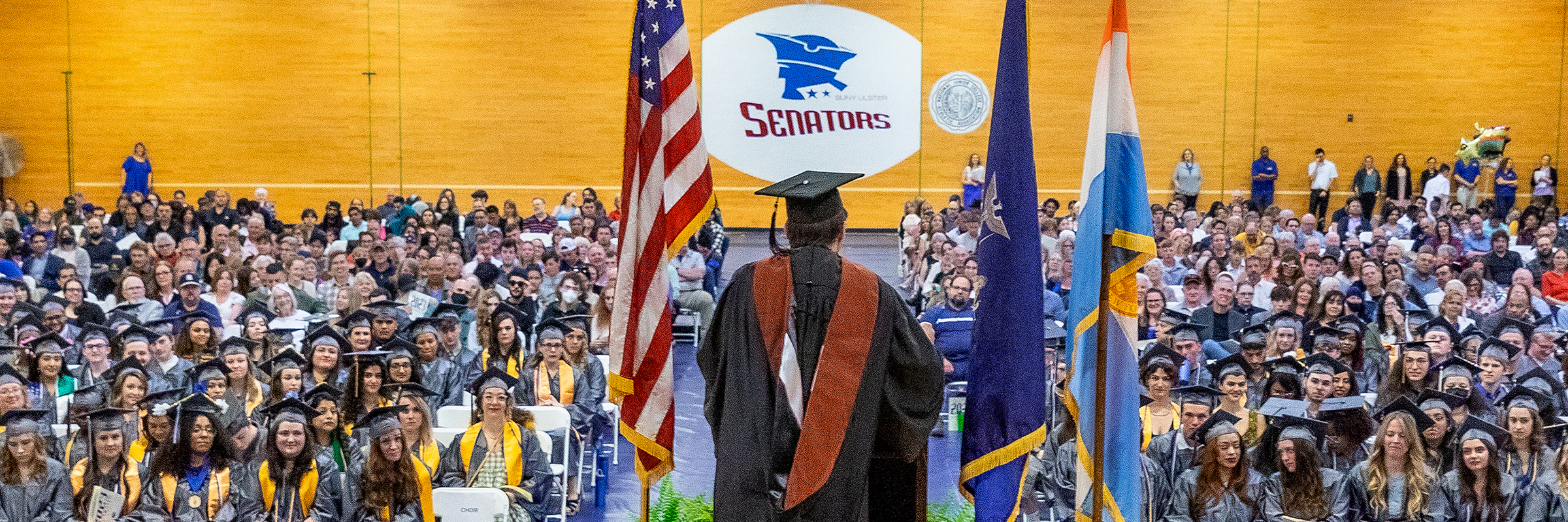 graduation ceremony with seated audience in caps and gowns