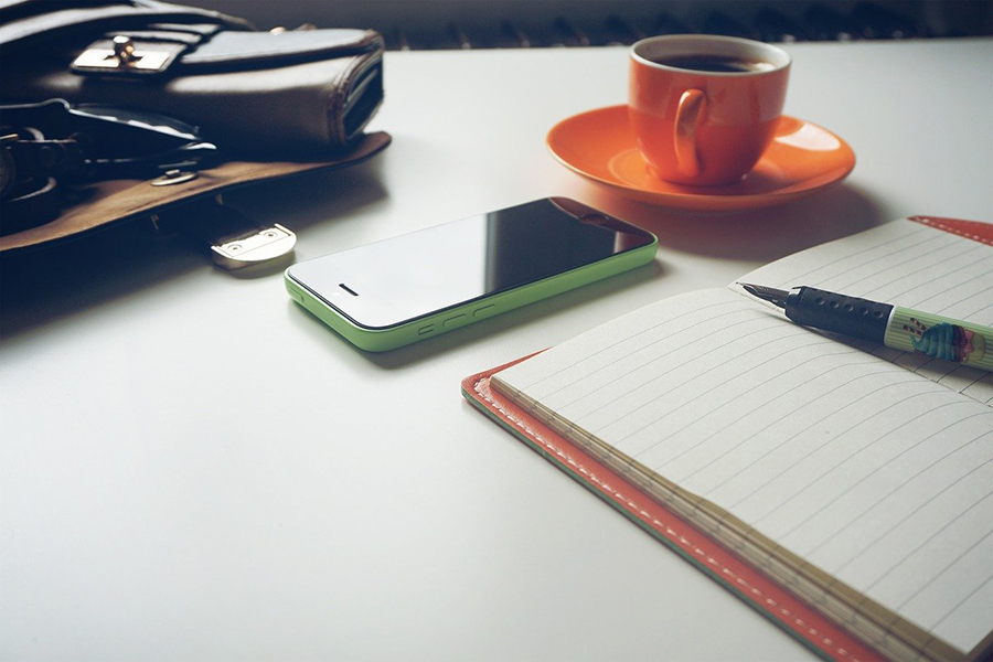 phone, coffee, notebook, pen, bag, on desk