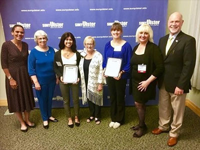 Students holding awards with Anita Williams Peck