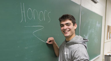 Student writing honors on chalkboard