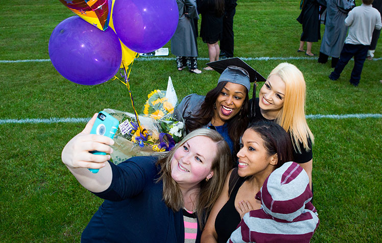 students posing for selfie with balloons at graduation