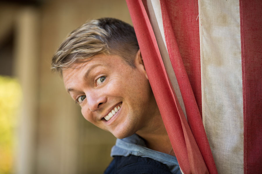 man peeking around corner and smiling