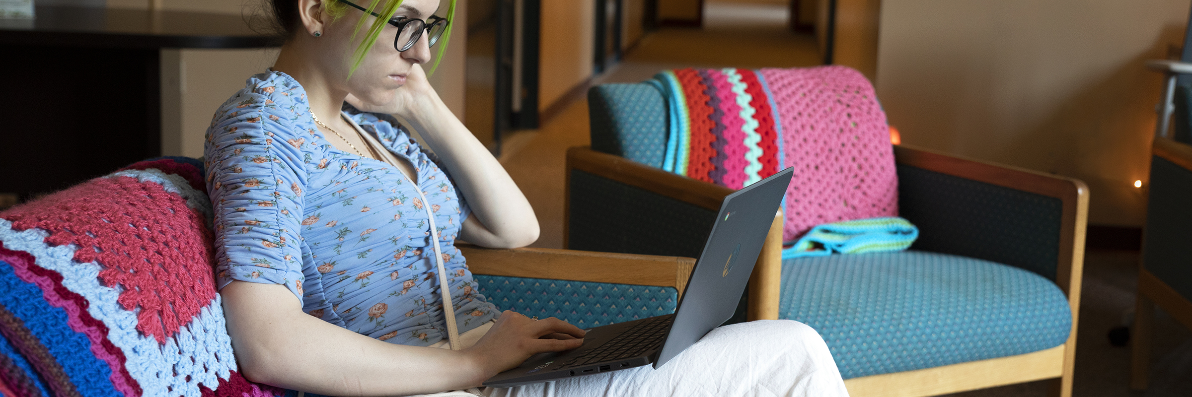 student with green hair on laptop in zen den